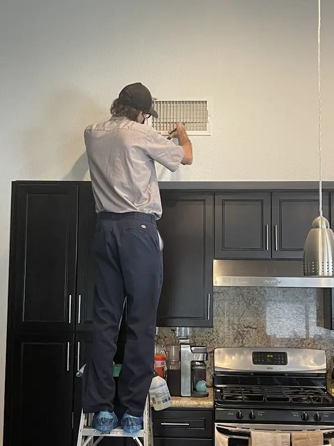 Technician inspecting an air vent during HVAC service in Micco
